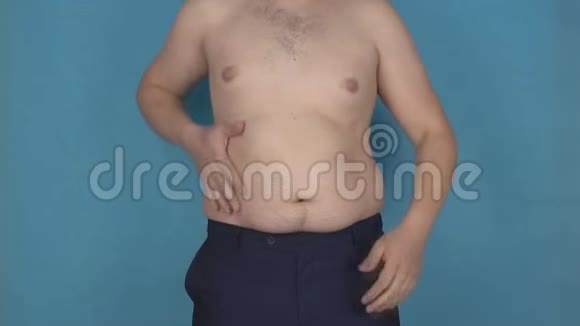 一个年轻人在厚厚的反脂肪胃上摩擦他的脂肪皱褶这是一种错误的生活方式和营养的概念视频的预览图