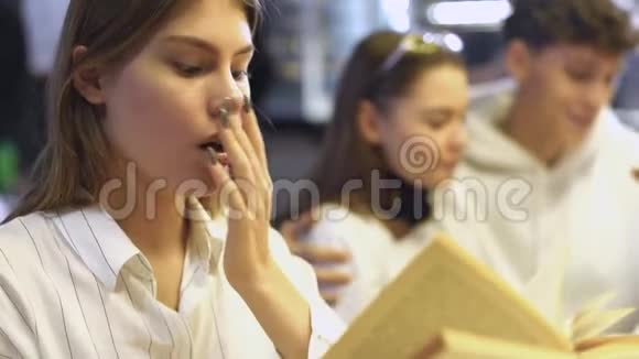 美丽疲惫的女孩读了一本书打了个哈欠决定躺在桌子旁在食堂里自己动手视频的预览图