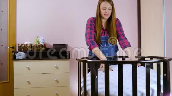 一名年轻孕妇为新生儿做准备折叠儿童木制的视频的预览图