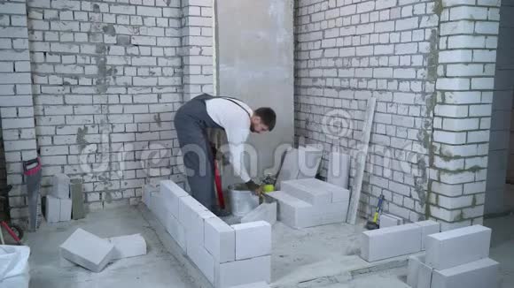 建筑工人在加气混凝土砌块两侧用抹刀放置粘接剂溶液视频的预览图