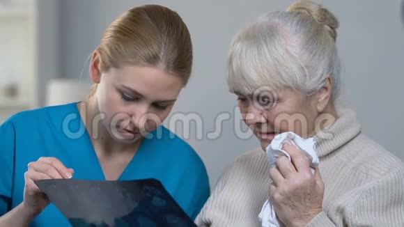 年轻医生给老年妇女看脑x光片并告诉她健康的好消息视频的预览图