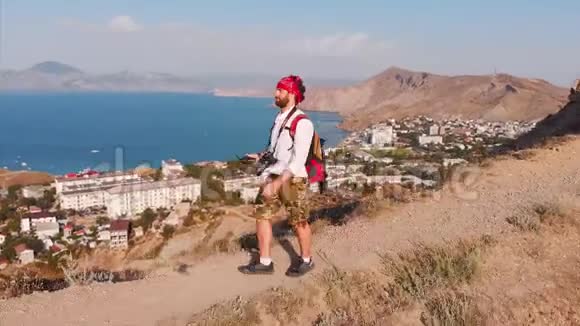 旅行的人带着背包和照相机穿过群山俯瞰着群山和山脉视频的预览图