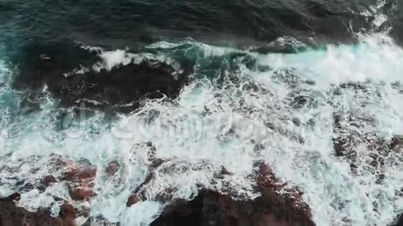 美丽的海浪拍打着岩石海滩近距离无人机射击视频的预览图