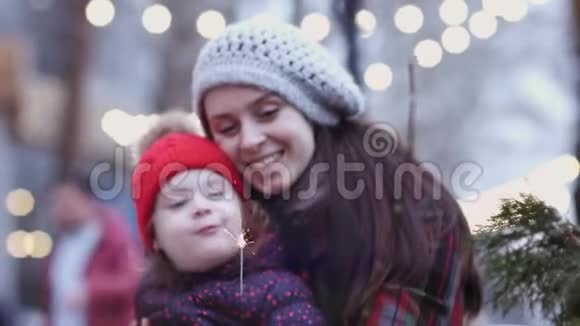 一位年轻的母亲抱着她的小女儿看着她闪闪发光幸福的家庭灯亮着视频的预览图