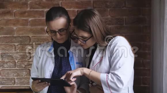 两个女医生拿着平板电脑女医生和女实习生谈论病人的诊断视频的预览图