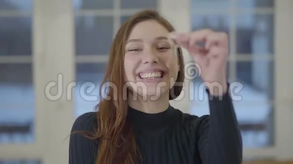 一个快乐自信微笑的女人的肖像在镜头前展示一套新房子或公寓的钥匙视频的预览图