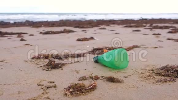 部分绿色塑料瓶被带到沙质海岸的岸边视频的预览图