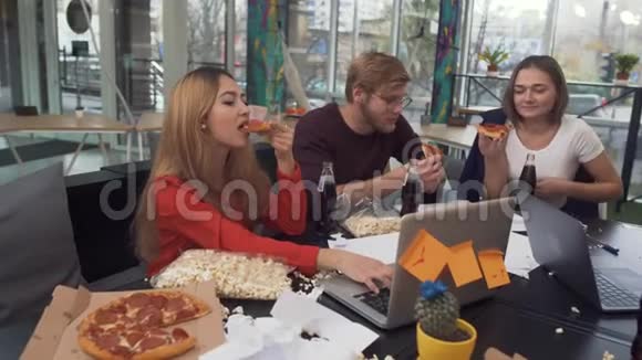 办公室的工作人员坐在桌子旁吃披萨在玻璃瓶里喝甜汽水视频的预览图