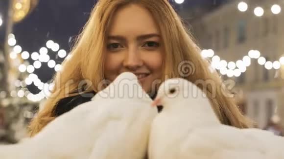 户外有两只美丽的白鸽的可爱女孩的肖像在街上过圣诞视频的预览图