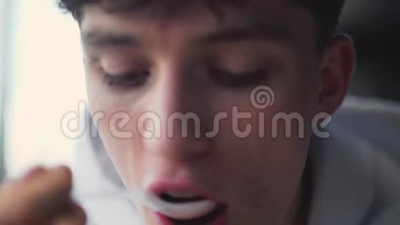 特写一个用勺子吃酸奶的家伙的脸视频的预览图