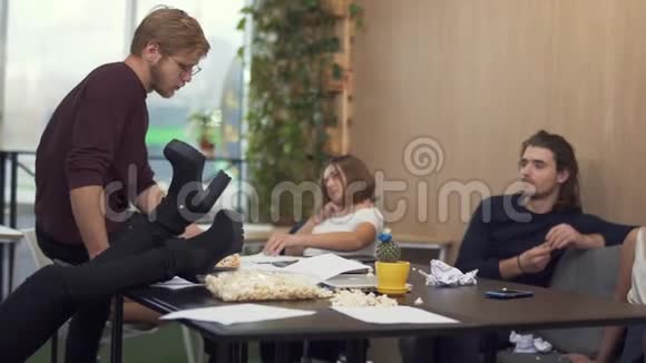 经过艰苦的工作队员们休息了一会儿一名员工把腿扔到桌子上每个人都吃爆米花视频的预览图