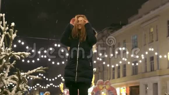 快乐的女人在雪下在户外跳舞快乐的女士在街上跳来跳去视频的预览图