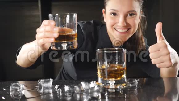 快活的女酒保用大拇指对着镜头微笑酒吧柜台上漂亮的女孩微笑着高清高清视频的预览图