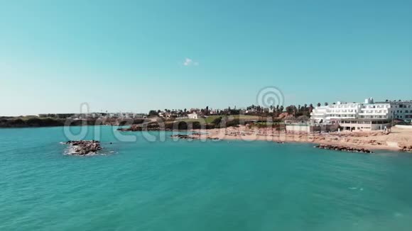珊瑚湾塞浦路斯航空拍摄与酒店和沙滩和蓝色的水在炎热的晴天沙滩无人驾驶飞机与人们一起视频的预览图