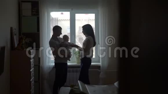 母亲和父亲与婴儿玩耍的剪影视频的预览图