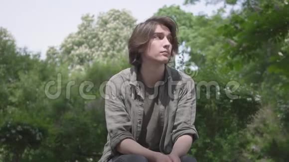 一个孤独紧张的年轻人坐在公园的长凳上等他的朋友或女朋友那个家伙视频的预览图