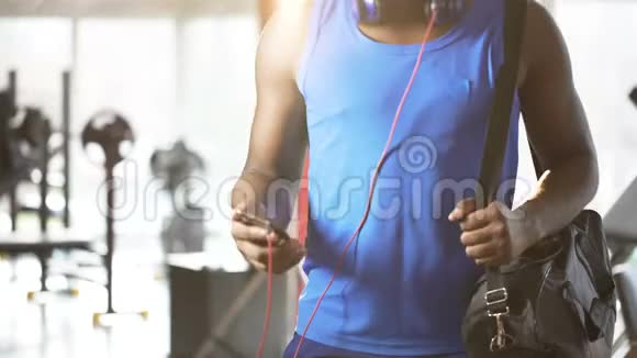 年轻人在健身房里用智能手机听励志音乐跳舞积极的生活方式视频的预览图