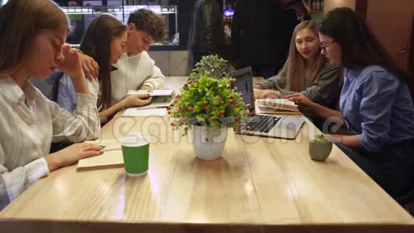 年轻人坐在桌子旁的咖啡馆里读杂志和书学生们花时间吃快餐健康饮食视频的预览图
