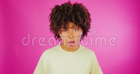 一个年轻的卷曲非洲女孩在粉红色的背景上愤怒抱怨愤怒生动的情感肢体语言视频的预览图