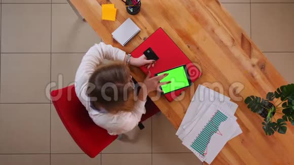 为年轻的高加索女商人在平板电脑上网上购物而拍摄的特写镜头办公室内有绿色屏幕视频的预览图