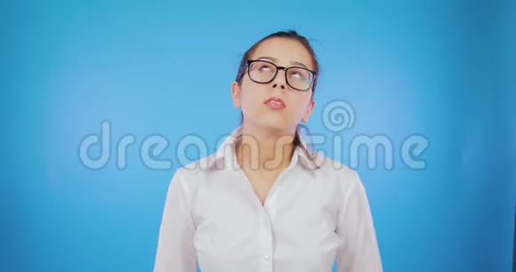 一个戴眼镜的疲惫的学生女孩解开了她的头发开始在蓝色的背景上跳舞打破规则自由视频的预览图