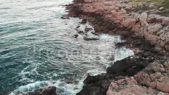 鸟瞰风暴的大海和巨浪用绿色草坪撞击岩石海滩视频的预览图