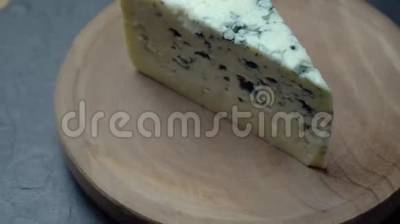 带有霉菌的奶酪在深色背景的木盘上旋转视频的预览图