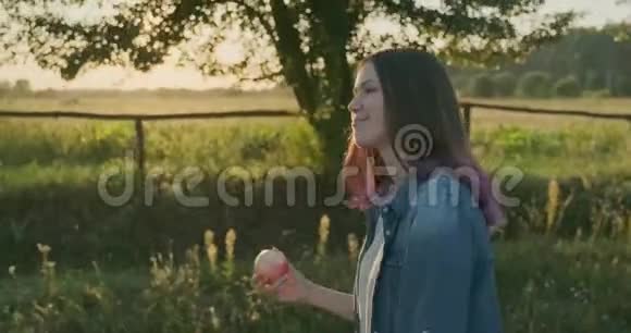 年轻快乐的女孩走着吃着红苹果自然健康的食物视频的预览图