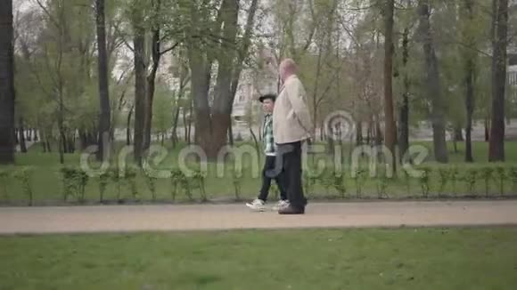 可爱的爷爷和可爱的小孙子一起在公园里散步世代概念友好家庭视频的预览图