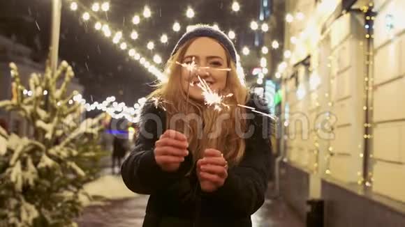 年轻微笑的女人在户外手中拿着火花的肖像星团向不同方向散射视频的预览图
