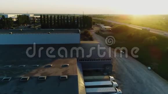 日出时在绿野附近有卡车的仓库大楼视频的预览图