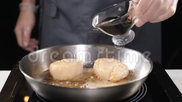 做海鲜健康的食物概念厨师在手套烹饪扇贝在缓慢的运动中倒入深色酱汁高清高清视频的预览图
