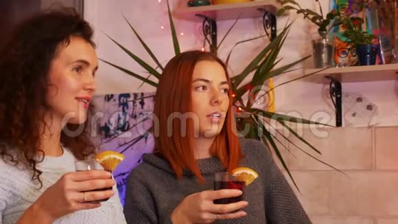 在一个节日的聚会上手里拿着一杯覆盖着酒的女孩们互相交流视频的预览图
