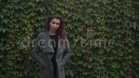 年轻漂亮的黑发女人穿着外套带着复印空间慢镜头微笑视频的预览图