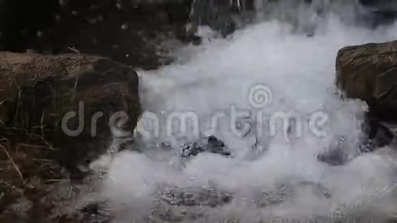 纯白色的瀑布从苔藓覆盖的岩石瀑布下流入水池视频的预览图