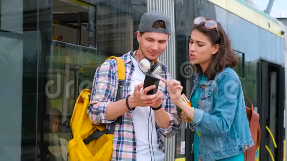 微笑的女孩帮助迷路的男游客找到路迷路的游客找路背景电车站视频的预览图