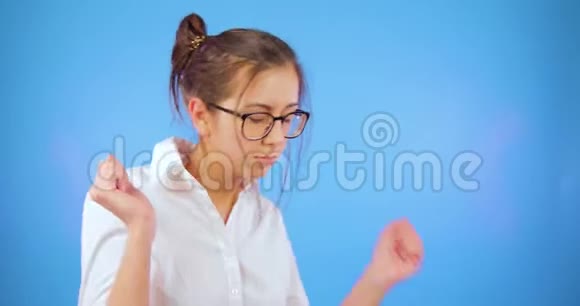戴眼镜的年轻女孩在蓝色背景上跳舞白色衬衫学生夜生活俱乐部视频的预览图