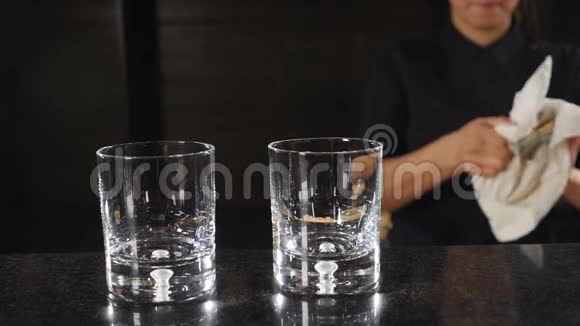 酒吧概念无法辨认的黑衣女酒保在吧台边擦着吉格杯慢动作高清视频的预览图