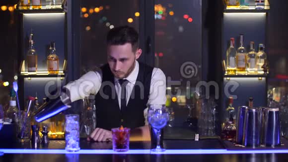 酒保在玻璃杯中倒入准备好的鸡尾酒视频的预览图