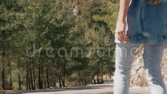 穿着牛仔裤的小树女人穿着牛仔裤走在森林的路上视频的预览图