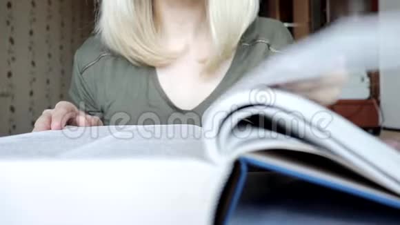 模糊而不可辨认的金发女人翻阅着一本大书学习和教育概念视频的预览图