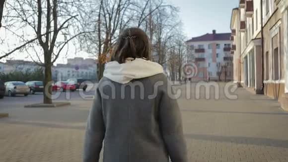 在秋天或春天的城市里一个女人穿着外套散步视频的预览图