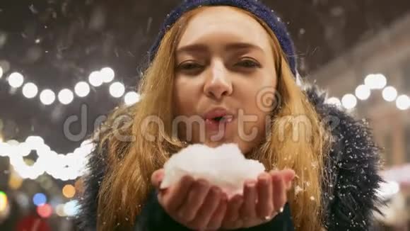 可爱的年轻女子在手里吹雪的肖像雪向不同方向散射视频的预览图