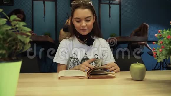 美丽的少女正在翻阅一本书突然紧张起来把书扔到地上视频的预览图