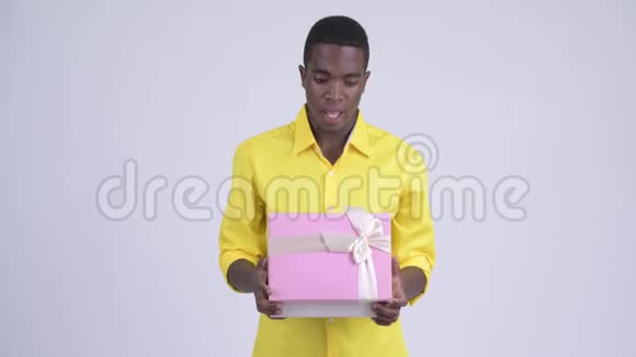 年轻快乐的非洲商人打开礼物盒看上去很惊讶视频的预览图