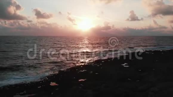 在美丽的粉红色日落和壮丽的多云天空中Dran沿着岩石海岸飞翔视频的预览图