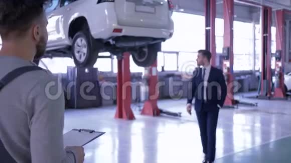 客户与汽车维修服务代表握手并在车辆背景上给车钥匙视频的预览图