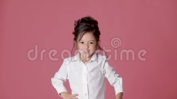 可爱的小女孩穿着白色衬衫在粉红色的背景上表现出不同的情绪视频的预览图