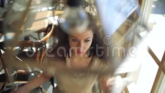 一个卷发的女人坐在咖啡馆的窗户里把头发伸直上文视视频的预览图