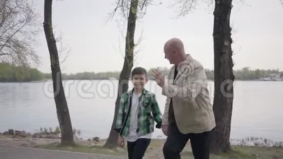 肖像可爱的祖父和可爱的小孙子一起在公园里散步世代概念友好视频的预览图